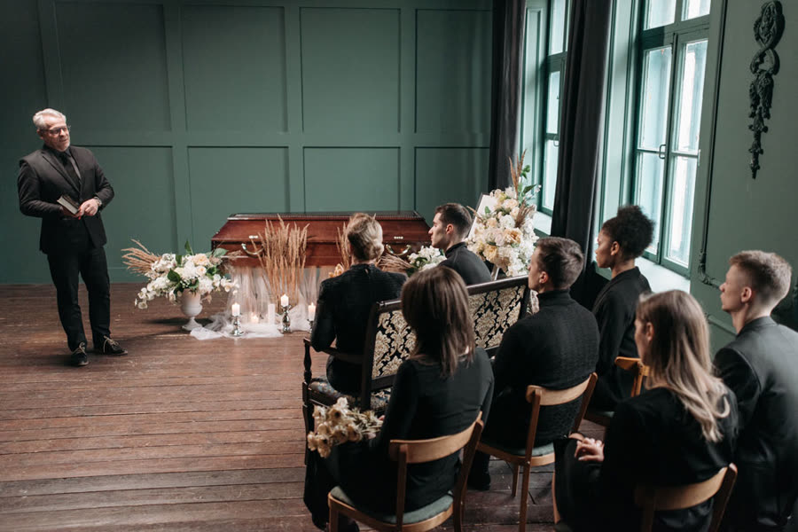 Afscheidsdienst in een aula, de spreker staat vooraan